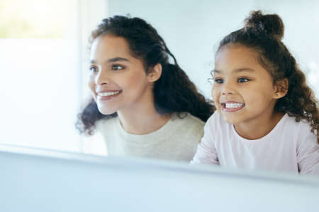 Dont they just look so pretty. Shot of a young mother and daughter admiring their clean teeth in a...