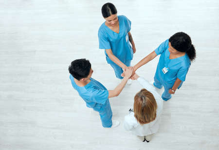 Hope in scrubs. Above shot of a group of medical practitioners joining their hands together in a huddle.の写真素材