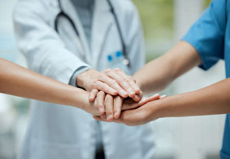 Pact of blood. Shot of a group of medical practitioners joining their hands together in a huddle.