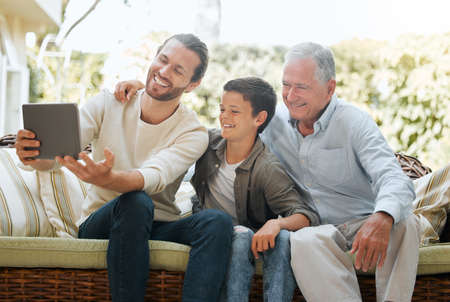Three generations of handsomeness. Shot of a man using a digital tablet while sitting outside with...