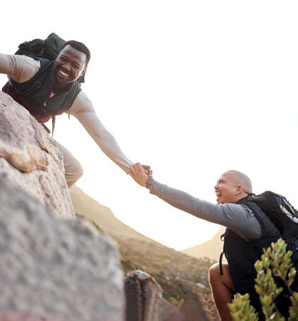 A helping hand. Cropped shot of a handsome young man helping his friend along a mountain during...