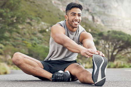 Stretching is a walk in the park. Shot of an athletic young man stretching on a mountain road.