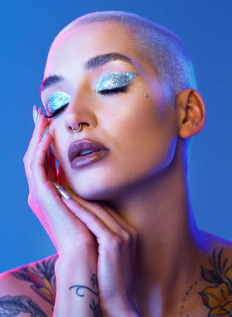 Feminine but with some spice. Studio shot of an attractive young woman wearing edgy makeup against a blue background.の写真素材