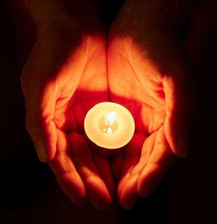 How far would you go to keep the hope. Shot of a unrecognizable person holding a candle in the dark.