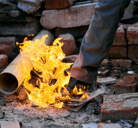 If you play with fire, youre gonna get burned. Shot of a unrecognizable man stepping on a burning...