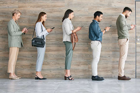 Technology helps with the wait. Full length shot of a diverse group of businesspeople standing in a...