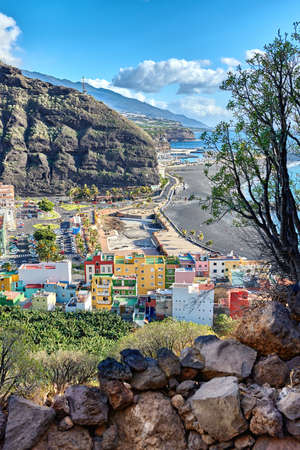 Colorful town houses or holiday resort accommodation near the seaside in a beautiful tourism destination, La Palma, Spain. An ocean coast with black beach sand on Puerto de Tazacorte beach from aboveの写真素材