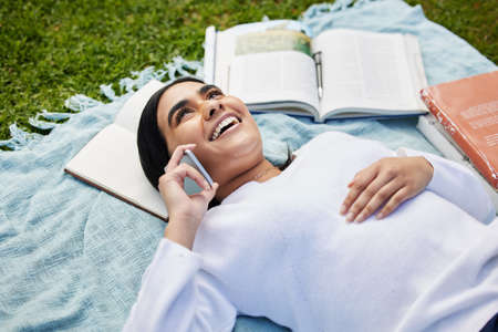 Finding images in the clouds. a young student taking a break from studying outside to make a phone call.の写真素材