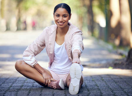 I always start with this stretch. Portrait of a sporty young woman stretching her legs while exercising outdoors.の写真素材