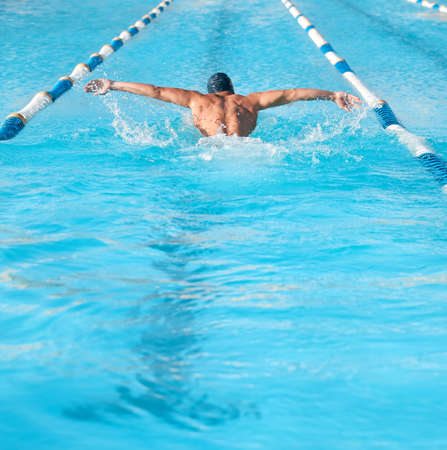 Moving like a butterfly. an unrecognizable young male athlete swimming in an olympic-sized pool.の写真素材