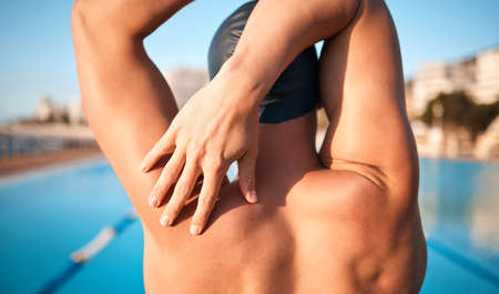 Stretching before his swim. Rearview shot of an unrecognizable young male athlete strecthing before...