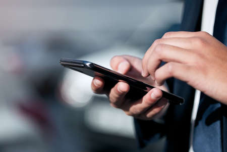 An update just came through. Closeup shot of an unrecognisable businessman using a cellphone while...
