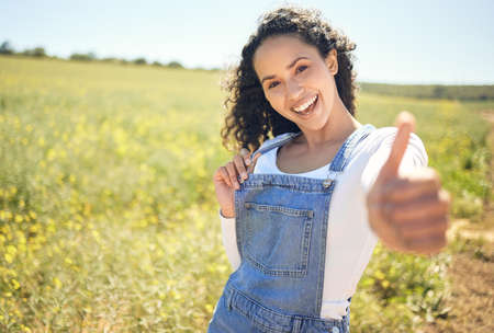 This is a great place to be. a beautiful young woman showing thumbs up while standing outdoors.の写真素材