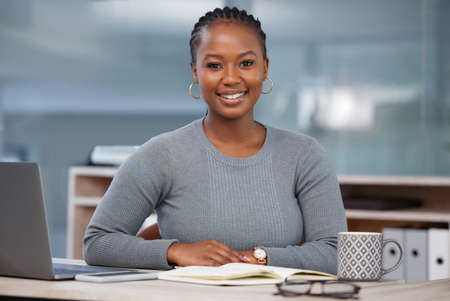 Working hard to achieve my goal. a beautiful young businesswoman in her office.の写真素材