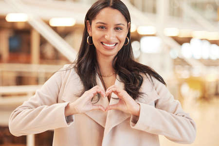 My love for shopping will never die. a beautiful young woman creating a heart shape with her hand while shopping.の写真素材