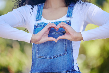 Respond with love. an unrecognizable woman forming a heart shape while standing outdoors.の写真素材