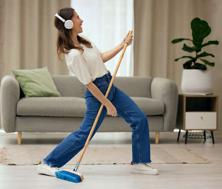Nothing quite like being in your own space. a young woman singing while sweeping the floors at home.の写真素材