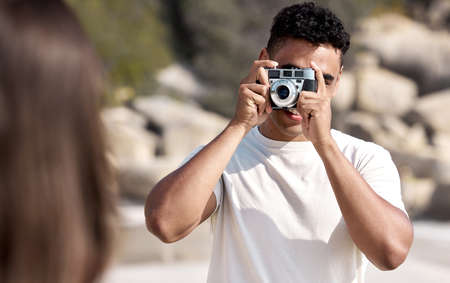 Pose for the picture. a young man taking pictures of his girlfriend at the beach.