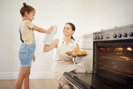 Another successful batch. a young mother and daughter giving each other a high five while baking at home.の写真素材
