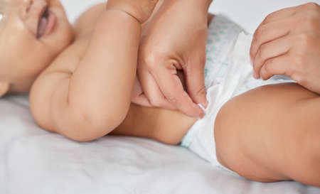 Thanks mum. an unrecognisable woman changing her babys diaper at home.