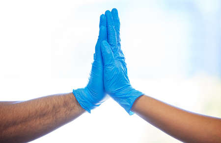 Teaming up to take on the world of teeth. two unrecognisable dentists giving each other a high five.