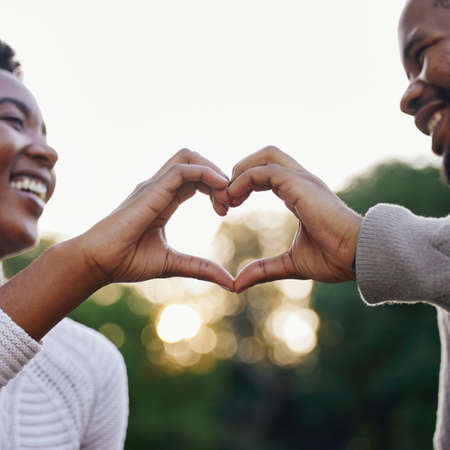 Our love is unconditional. a young couple making a heart gesture with their hands in nature.