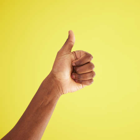 Dont just like it, love it. Studio shot of an unrecognisable man showing thumbs up against a yellow...