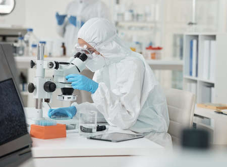 Its clear to see now. a scientist wearing a radiation suit while using a microscope in a lab.