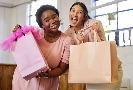 Weve got just what you need. Cropped portrait of two attractive young female business owners holding shopping bags while standing in their store.の写真素材