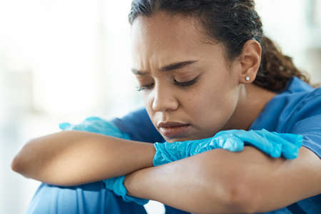 Hardships often prepare people for an extraordinary destiny. a female nurse looking stressed while sitting in a hospital.の写真素材