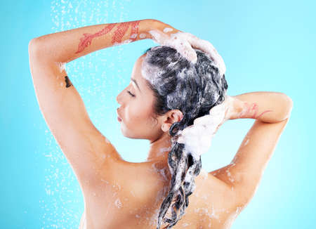 Let me walk you through my haircare routine. a woman washing her hair against a blue background.の写真素材