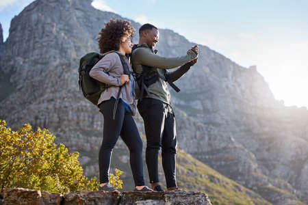 Thats an awesome shot. Full length shot of an affectionate young couple taking photos while out on an early morning hike.の写真素材