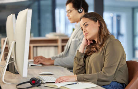 I wish I didnt have to be here. a young call centre agent looking bored while working in an office...