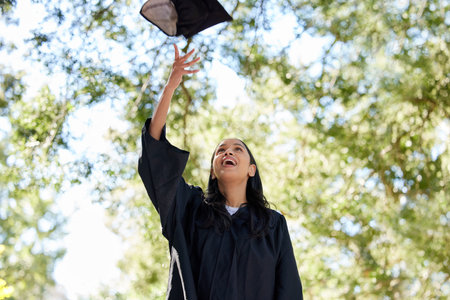 Its that time. an attractive young female graduate throwing her cap into the air outside.の写真素材