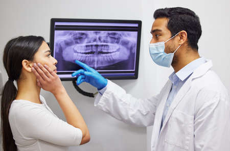 Your wisdom tooth is actually growing into your jaw bone. a dentist discussing the results of a patients teeth x ray.の写真素材
