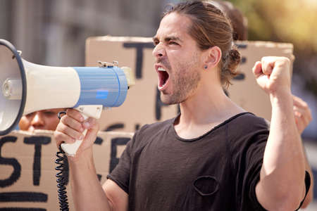 I will not rest until you surrender. a young man using a megaphone at a protest rally.