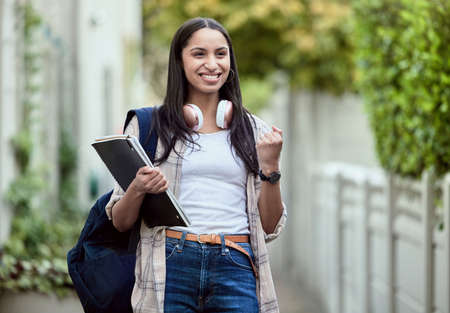 I aced that exam. an attractive young female student cheering while standing outside on campus.の写真素材