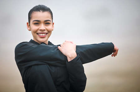 Stretching is always important. Cropped portrait of an attractive young female athlete warming up outside.の写真素材