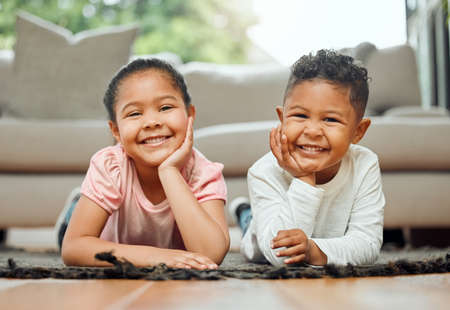Learning together. Portrait of two young siblings lying on the floor together at home.の写真素材