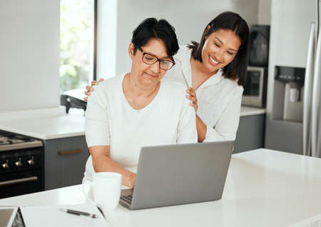 My daughter, my keeper. a young woman using a laptop with her elderly mother while going through...