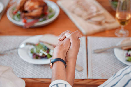 Well always have each other. two unrecognizable people holding hands at the dinner table at home.の写真素材