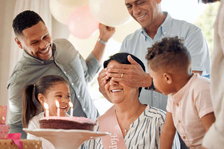 Can I open my eyes yet. a family surprising their mother with a birthday cake at home.