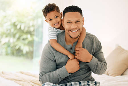 Extra hugs to get dad through the day. Portrait of a young father and son bonding together at home.