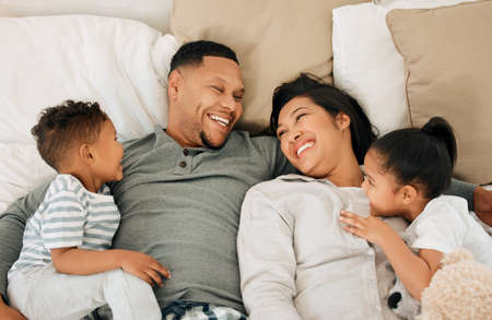 Prioritising healthy bonding. a beautiful young family talking and bonding in bed together.の写真素材