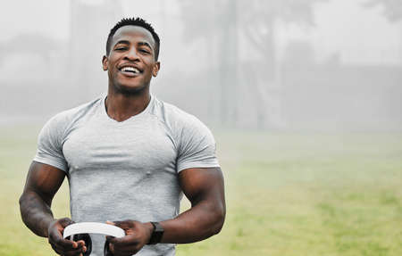 The music keeps me going. Cropped portrait of a handsome young male athlete holding a pair of headphones while exercising outside.の写真素材