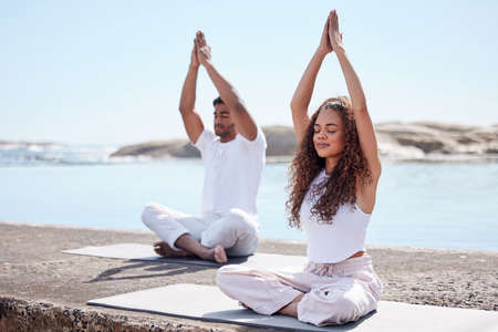 Feel it in your spirit. Full length shot of a young couple practicing yoga at the beach.