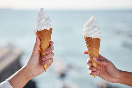 Hello sweet summer. Closeup shot of two unrecognisable women holding ice cream cones outdoors.の写真素材