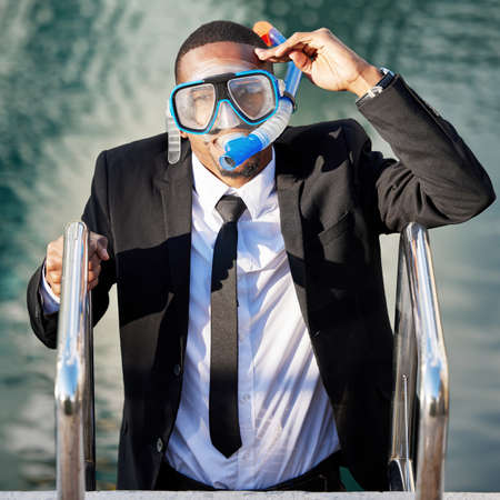 No longer drowning in debt. a businessman getting out of a pool while wearing scuba diving gear.の写真素材