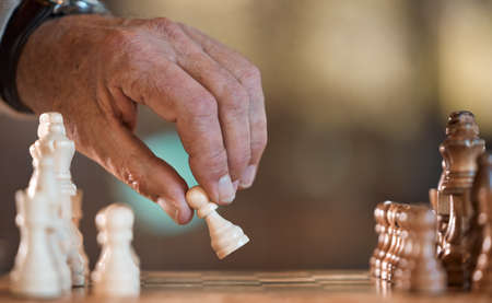 Chess is a mind game. an unrecognisable man playing a game of chess.