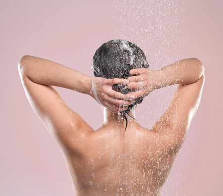 Ive never felt cleaner. a young woman washing her hair against a studio background.の写真素材